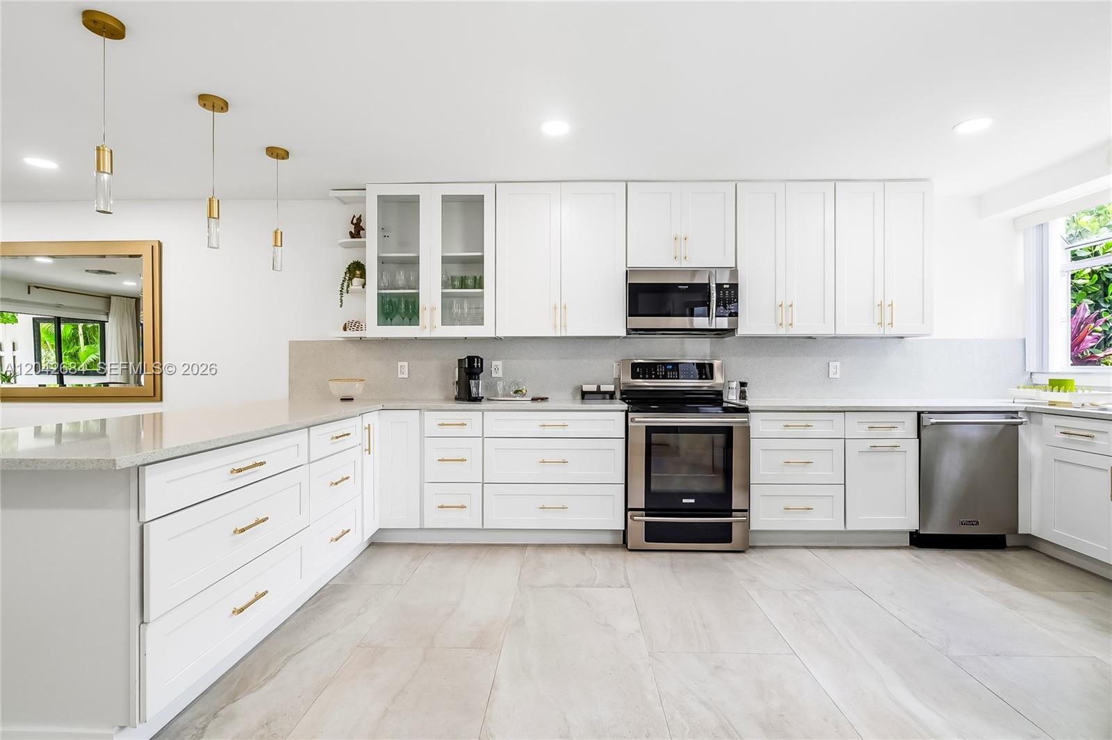 A modern kitchen features white cabinetry, stainless steel appliances, gold hardware, and light tile flooring — 1301 SW 10th Ave # 105, Delray Beach FL 33444, DELRAY BEACH, FL