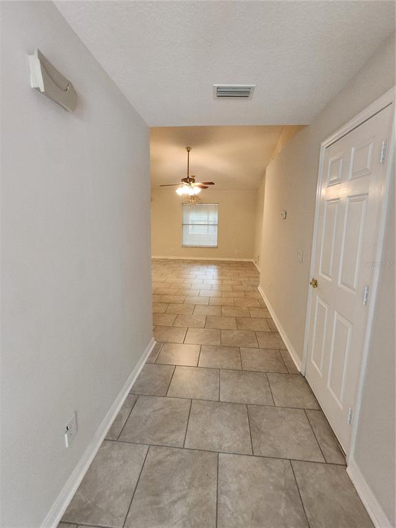 A tiled hallway leads into an open living area with a ceiling fan and window — 6521 E GRAYSON STREET, INVERNESS, FL