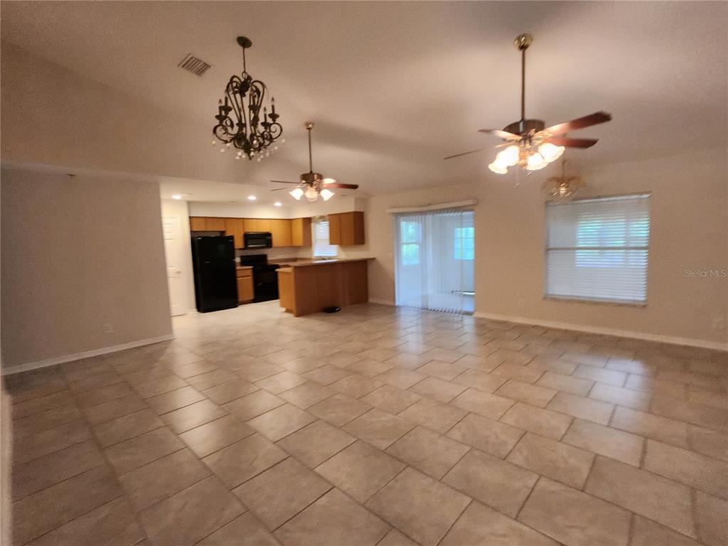 An open-concept living and kitchen area features tile flooring, ceiling fans, and wood cabinetry — 6521 E GRAYSON STREET, INVERNESS, FL