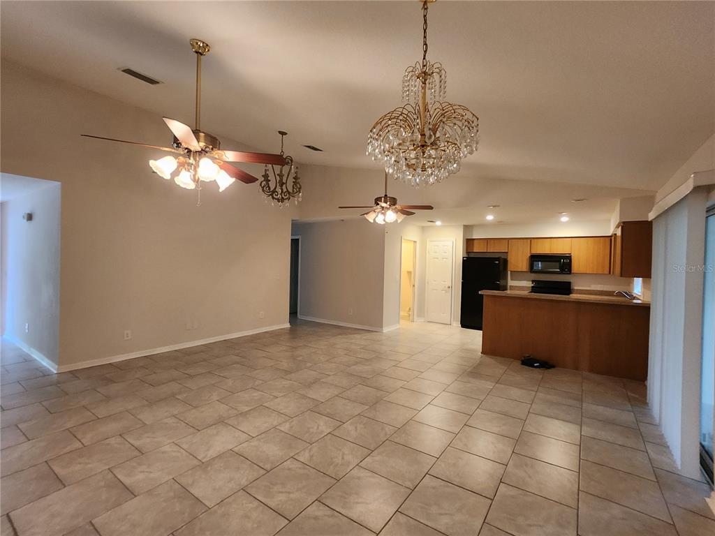 An open-concept living and dining area features tile flooring, two ceiling fans, and a chandelier — 6521 E GRAYSON STREET, INVERNESS, FL