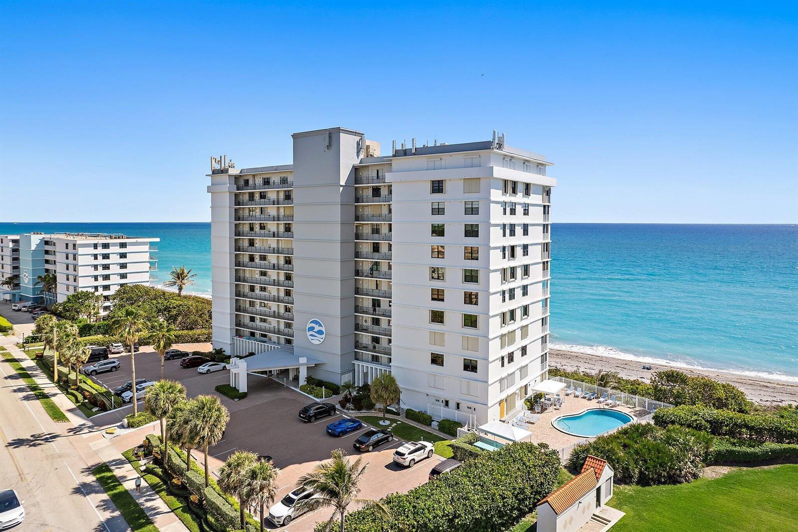 An aerial view of a multi-story beachfront condominium building with a parking lot and pool — 840 Ocean Drive # 905, Juno Beach FL 33408, JUNO BEACH, FL