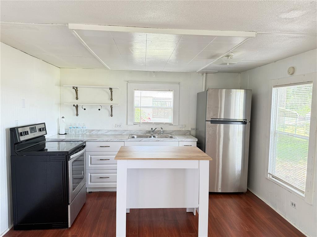 A kitchen with white cabinets, a wooden island, stainless steel refrigerator, and black stove — 3545 SW 90TH STREET, OCALA, FL