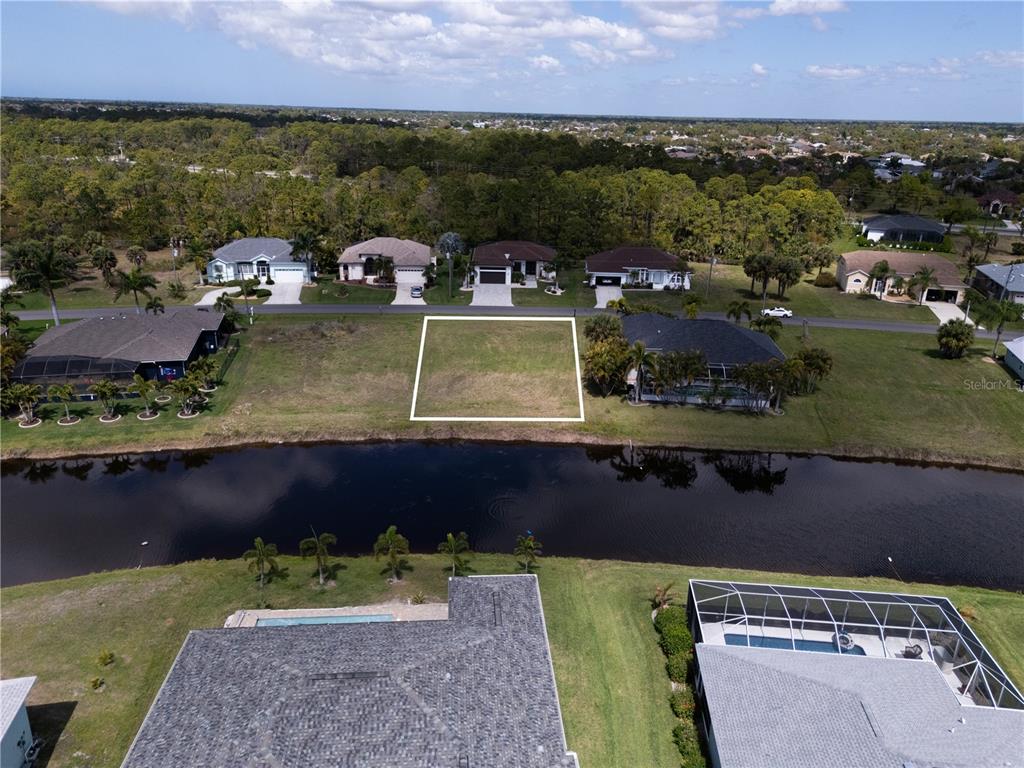 An aerial view shows a vacant residential lot situated between two houses along a canal — 132 WHITE MARSH LANE, ROTONDA WEST, FL
