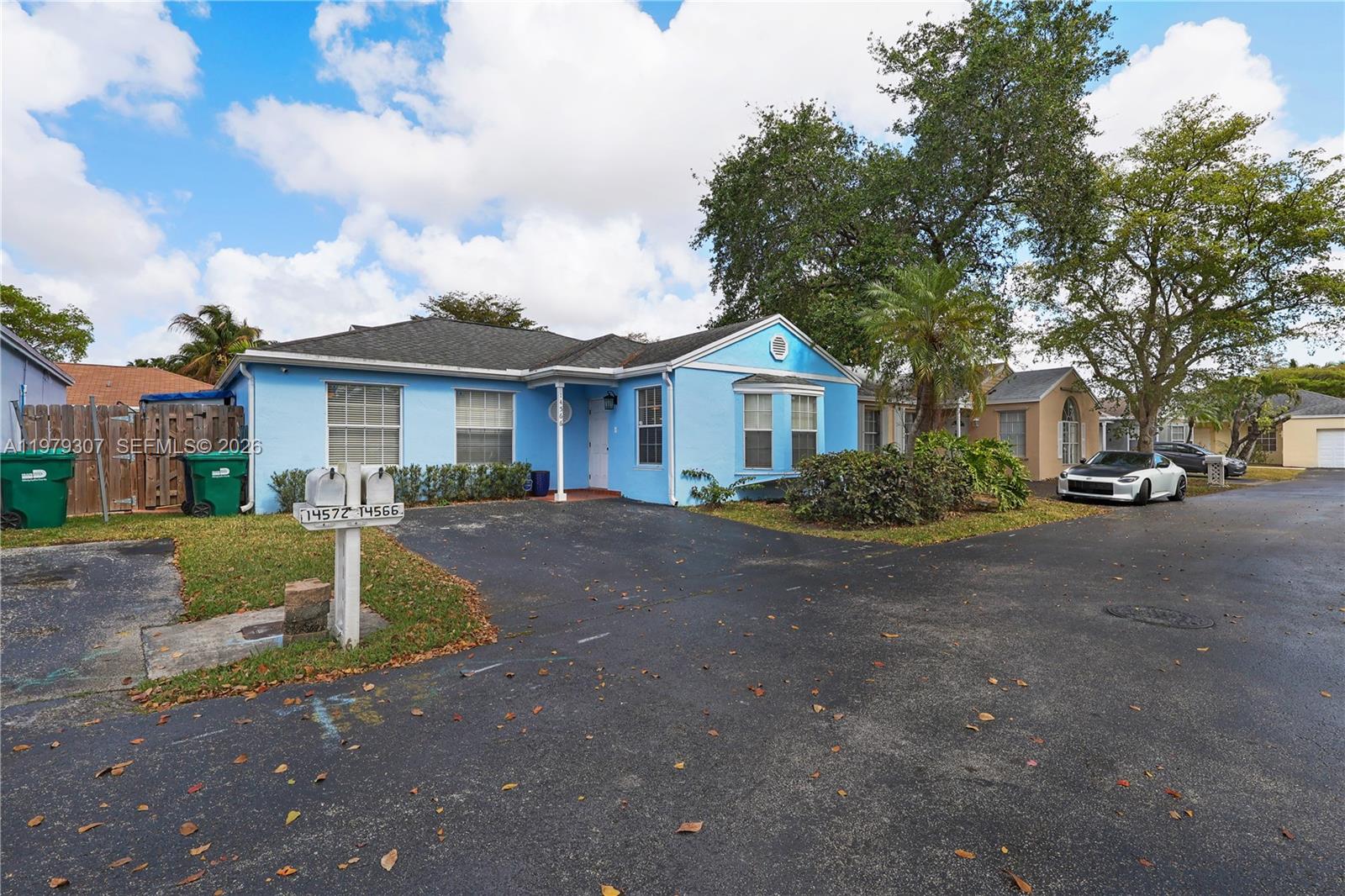 A light blue single-story house features a paved driveway, two mailboxes, and mature trees — 14566 SW 124th Pl, Miami FL 33186, MIAMI, FL