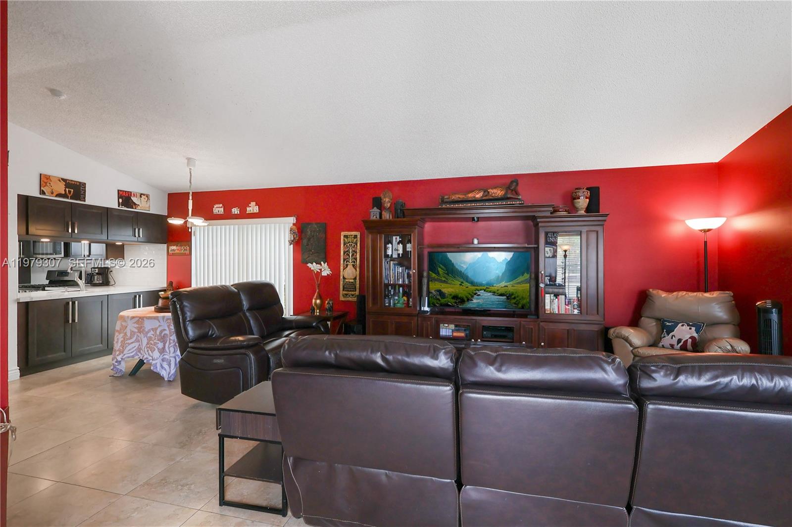 A living room with dark leather furniture, a large wooden entertainment center, and red walls — 14566 SW 124th Pl, Miami FL 33186, MIAMI, FL