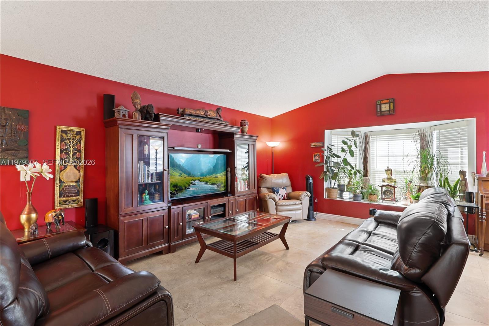 A living room features red walls, tile flooring, a large wooden entertainment center, and leather furniture — 14566 SW 124th Pl, Miami FL 33186, MIAMI, FL
