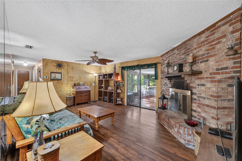 A living room features wood flooring, a brick fireplace, and a sliding glass door — 8204 SW 12TH PLACE, GAINESVILLE, FL