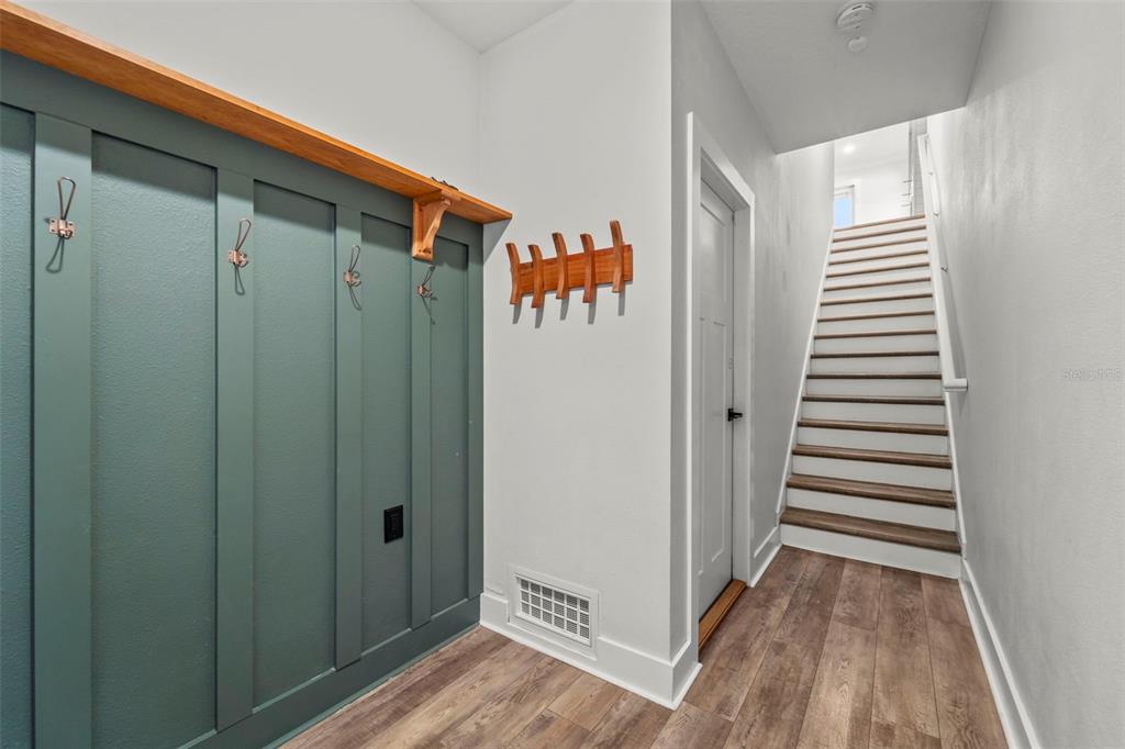A hallway features a teal paneled mudroom wall with hooks, a wooden shelf, and stairs — 1299 SAVONA DRIVE NE, ST PETERSBURG, FL
