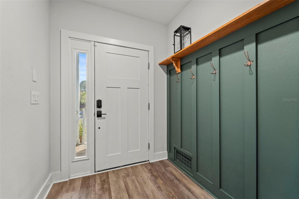 An entryway features wood-look flooring, a white front door, and a green paneled mudroom wall — 1299 SAVONA DRIVE NE, ST PETERSBURG, FL