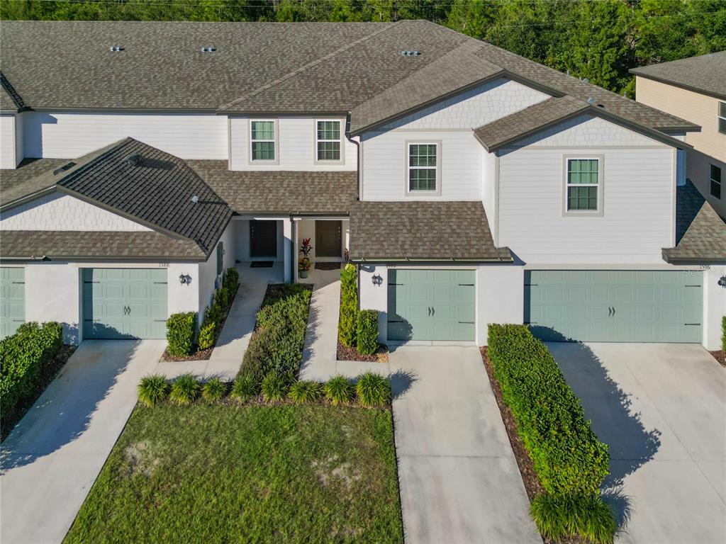 An aerial view shows the exterior of a multi-unit townhouse complex with attached garages — 1592 WYNFORD CIRCLE, TAVARES, FL