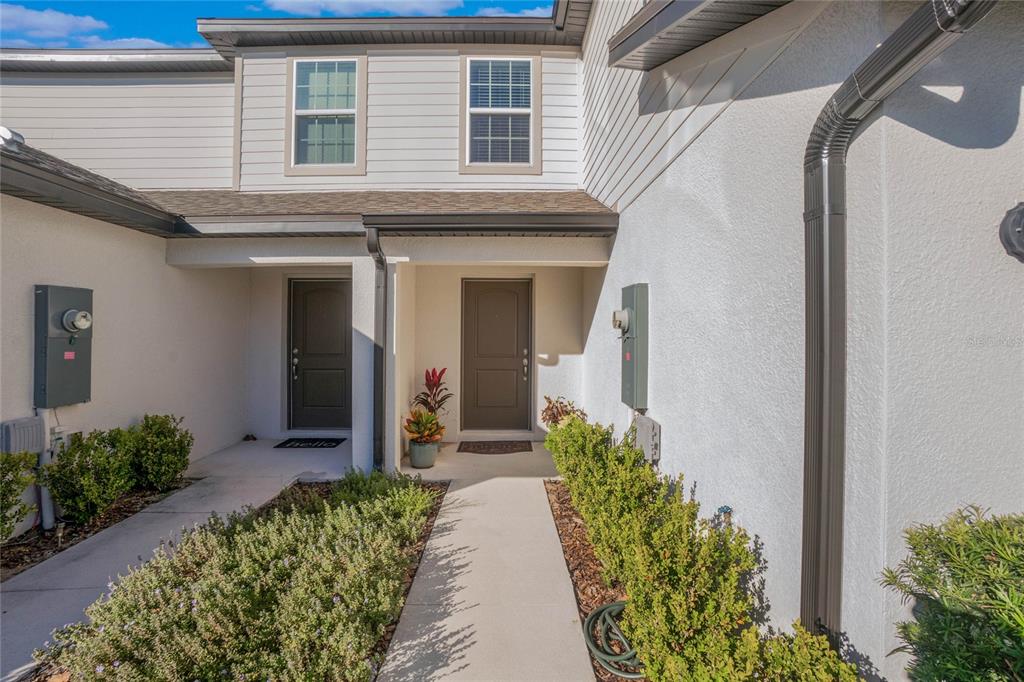 The exterior of a two-story townhouse features two dark brown front doors and landscaping — 1592 WYNFORD CIRCLE, TAVARES, FL