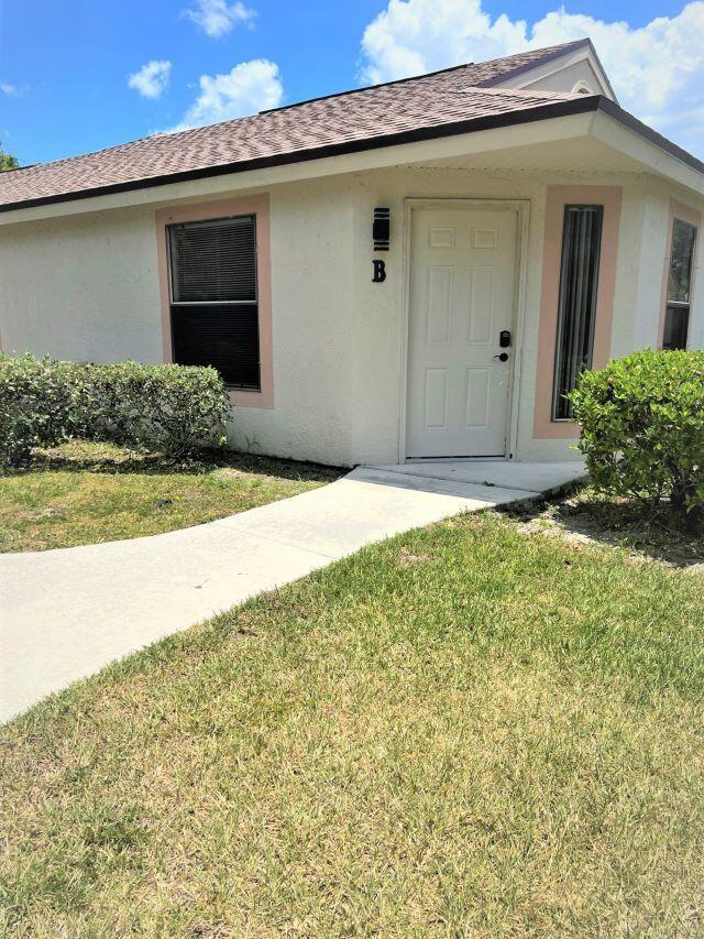 A single-story building exterior with a white door labeled B, a walkway, and landscaping — 2812 Stoneway Lane Unit B, Fort Pierce FL 34982, FORT PIERCE, FL