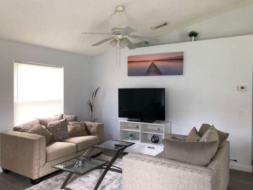 A living room features a beige sofa, a glass coffee table, and a wall-mounted television — 2812 Stoneway Lane Unit B, Fort Pierce FL 34982, FORT PIERCE, FL