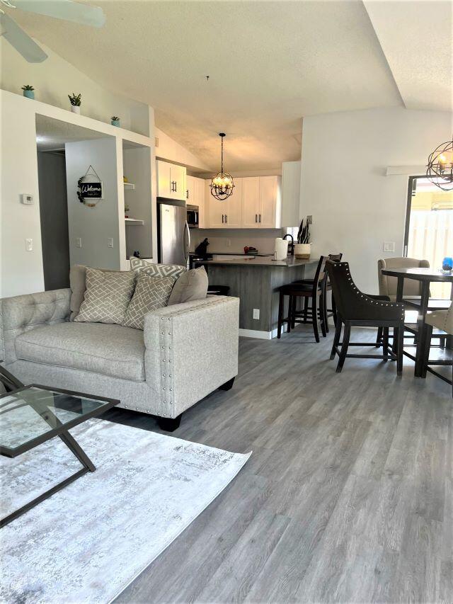 An open-concept living room and kitchen feature gray wood-look flooring and white cabinetry — 2812 Stoneway Lane Unit B, Fort Pierce FL 34982, FORT PIERCE, FL