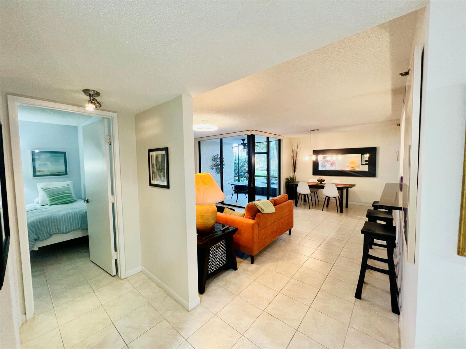 An interior view shows a tiled hallway leading to a bedroom, living area, and dining space — 2025 Lavers Circle # D107, Delray Beach FL 33444, DELRAY BEACH, FL