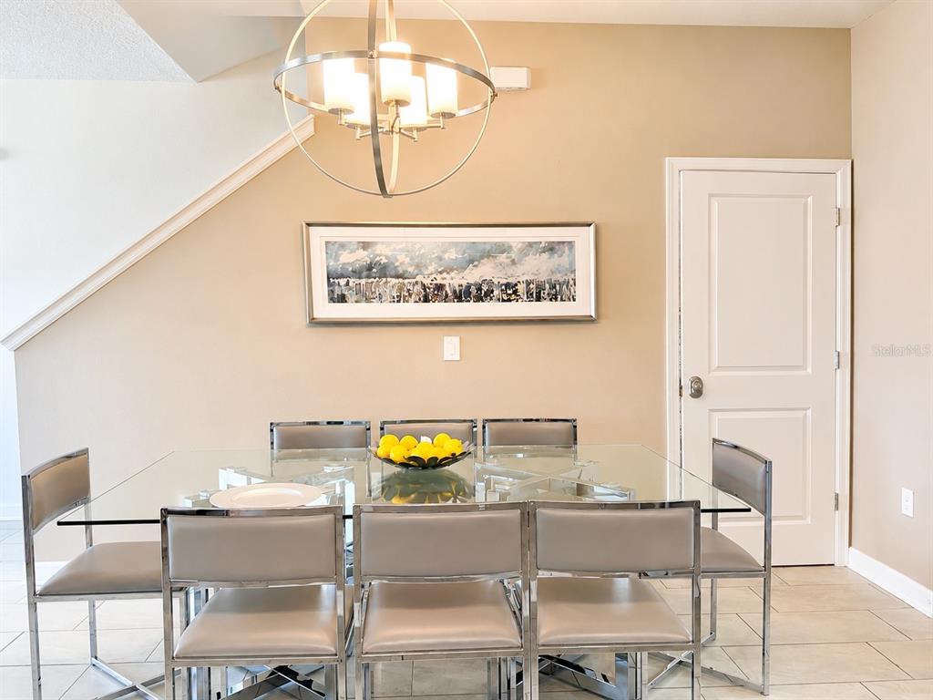 A dining room features a glass table, six silver chairs, and a modern orb chandelier — 8955 CABOT CLIFFS DRIVE, DAVENPORT, FL