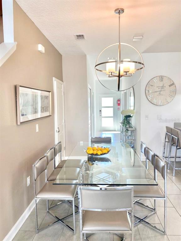 A dining area features a glass-topped table, six metallic chairs, and a spherical chandelier — 8955 CABOT CLIFFS DRIVE, DAVENPORT, FL