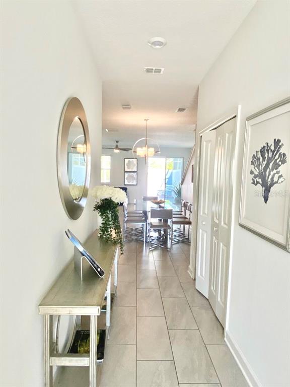 A hallway with a console table and mirror leads to a dining area with tile floors — 8955 CABOT CLIFFS DRIVE, DAVENPORT, FL