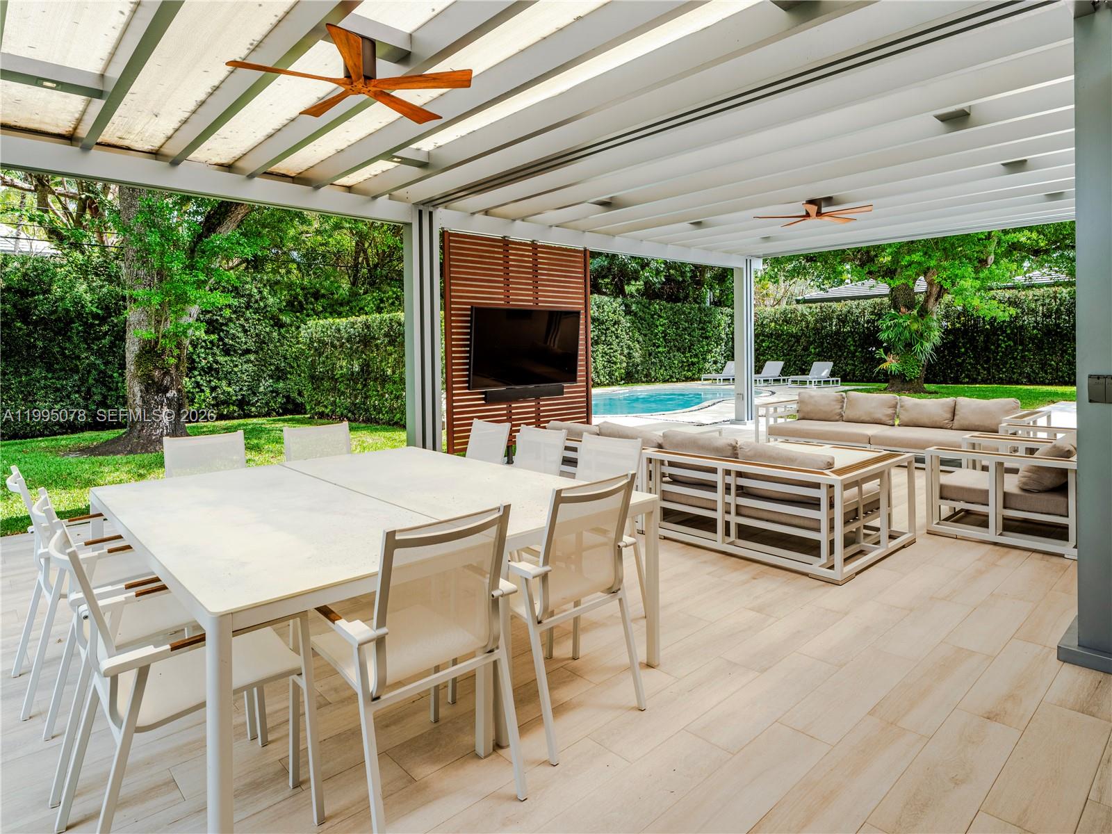 A covered outdoor patio features a dining set, lounge furniture, a television, and pool views — 8525 SW 54th Ct, Miami FL 33143, MIAMI, FL