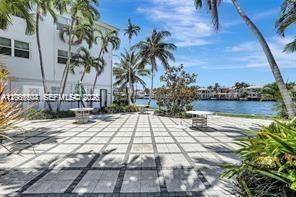 A paved patio with tables overlooks a canal lined with palm trees and residential buildings — 2600 S Ocean Dr # S306, Hollywood FL 33019, HOLLYWOOD, FL