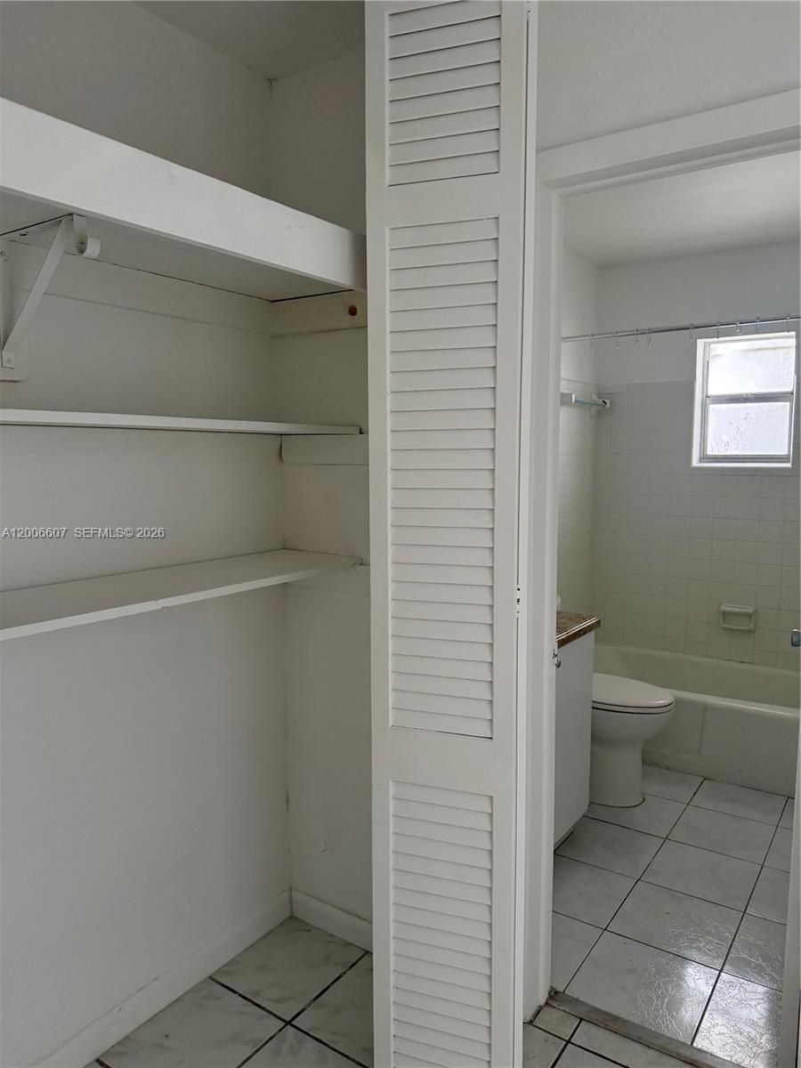 A white closet with open shelving stands next to a tiled bathroom with a tub — 2600 S Ocean Dr # S306, Hollywood FL 33019, HOLLYWOOD, FL