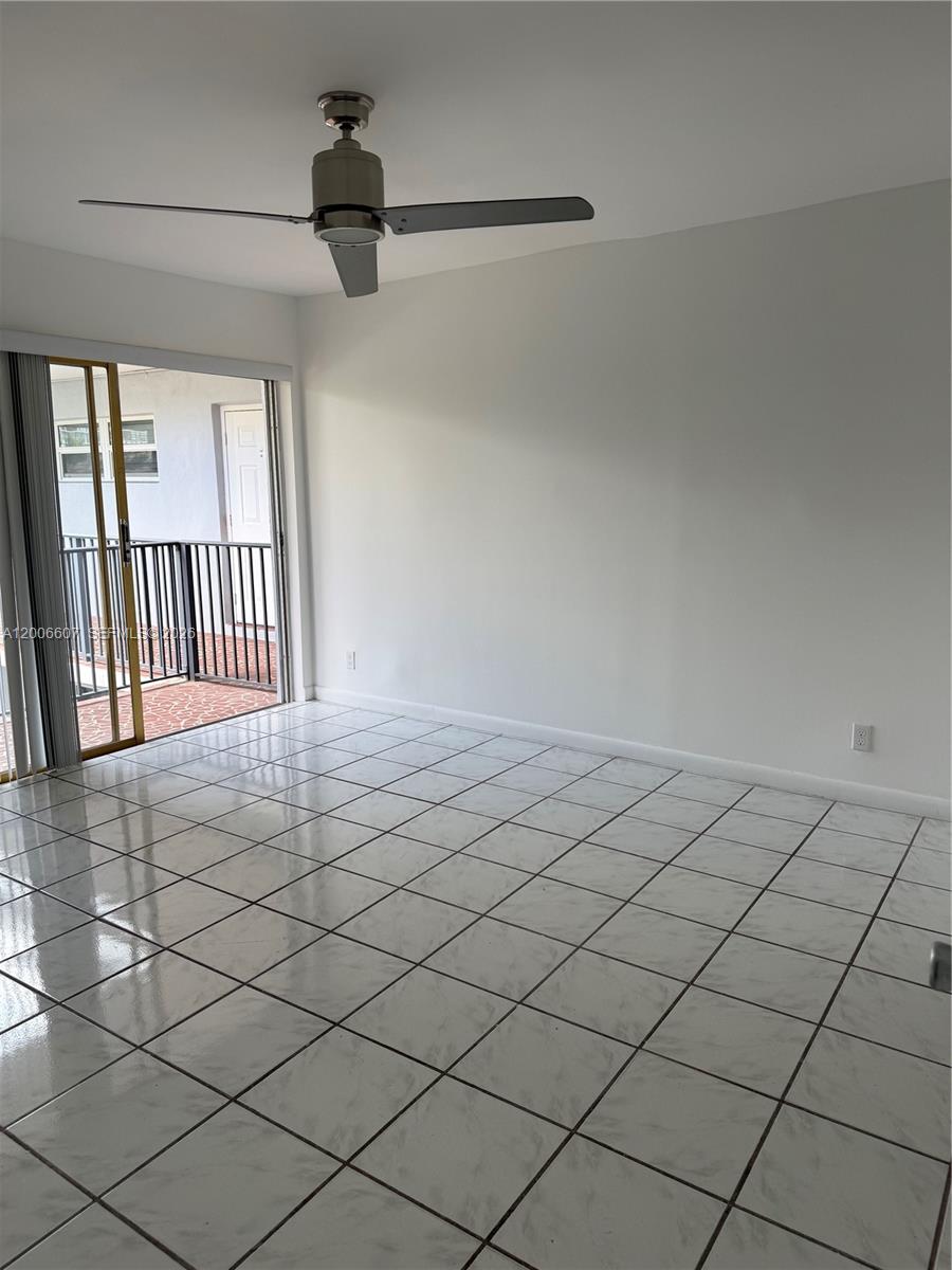 An empty room features white tiled floors, a ceiling fan, and a sliding glass door — 2600 S Ocean Dr # S306, Hollywood FL 33019, HOLLYWOOD, FL
