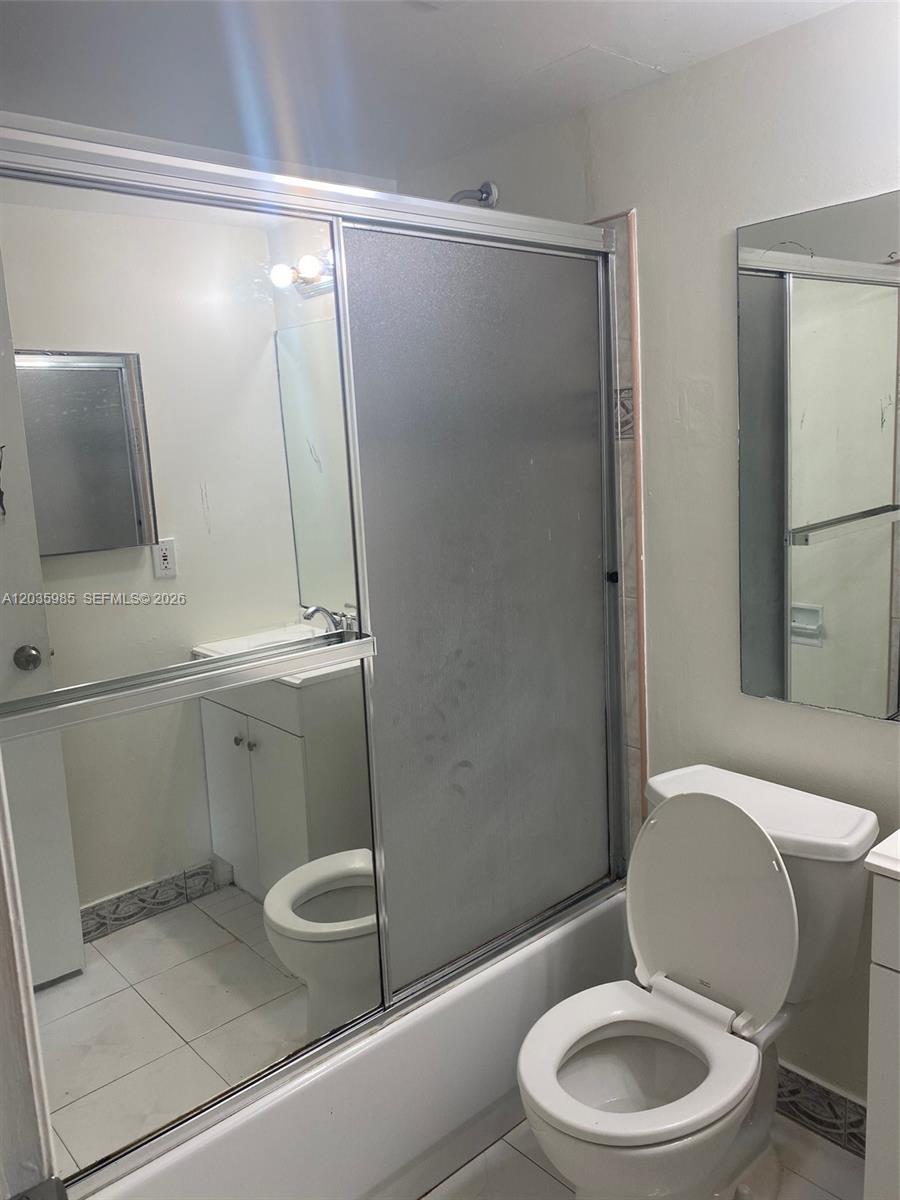 A bathroom features a white toilet, a bathtub with a sliding glass door, and mirrors — 15695 SW 82nd Cir Ln # 5, Miami FL 33193, MIAMI, FL