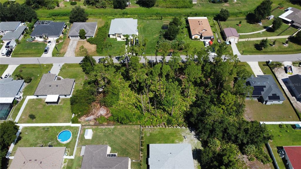 An aerial view shows a wooded vacant lot situated between several suburban residential houses — Lot 22 CLEARFIELD STREET, NORTH PORT, FL