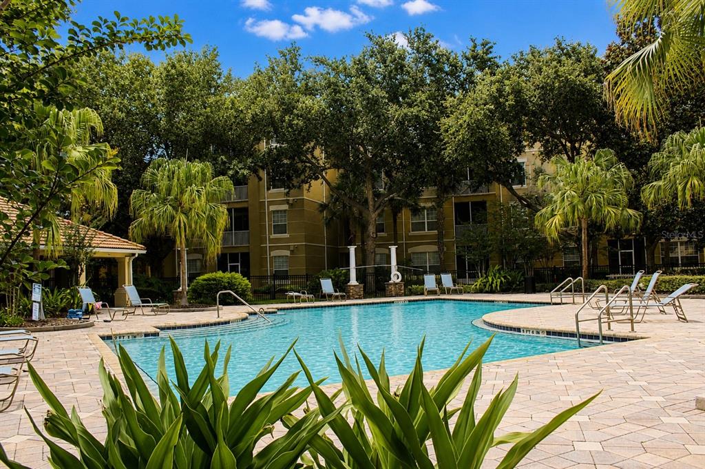 A swimming pool with lounge chairs sits in front of a multi-story apartment building — 3338 ROBERT TRENT JONES DRIVE UNIT 40104, ORLANDO, FL