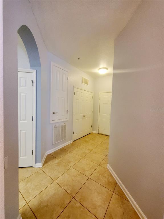 A hallway with tile flooring, an arched entryway, and several white interior doors — 3338 ROBERT TRENT JONES DRIVE UNIT 40104, ORLANDO, FL