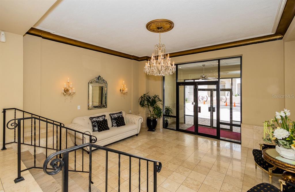 A lobby features a crystal chandelier, a white sofa, tiled floors, and glass entrance doors — 2109 BAYSHORE BOULEVARD UNIT 606, TAMPA, FL