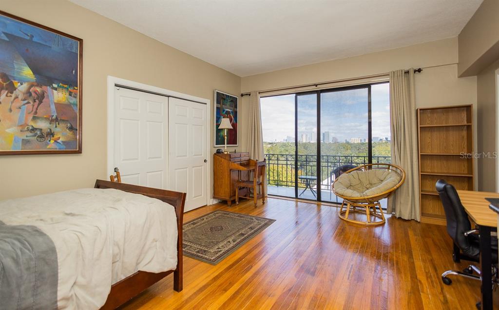 A bedroom with hardwood floors, a bed, a desk, a bookshelf, and a balcony view — 2109 BAYSHORE BOULEVARD UNIT 606, TAMPA, FL