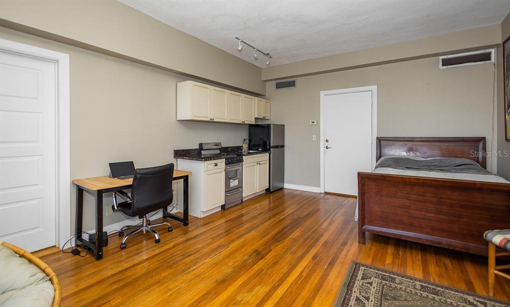 A studio apartment features a kitchenette, a wooden bed frame, and a desk on hardwood floors — 2109 BAYSHORE BOULEVARD UNIT 606, TAMPA, FL