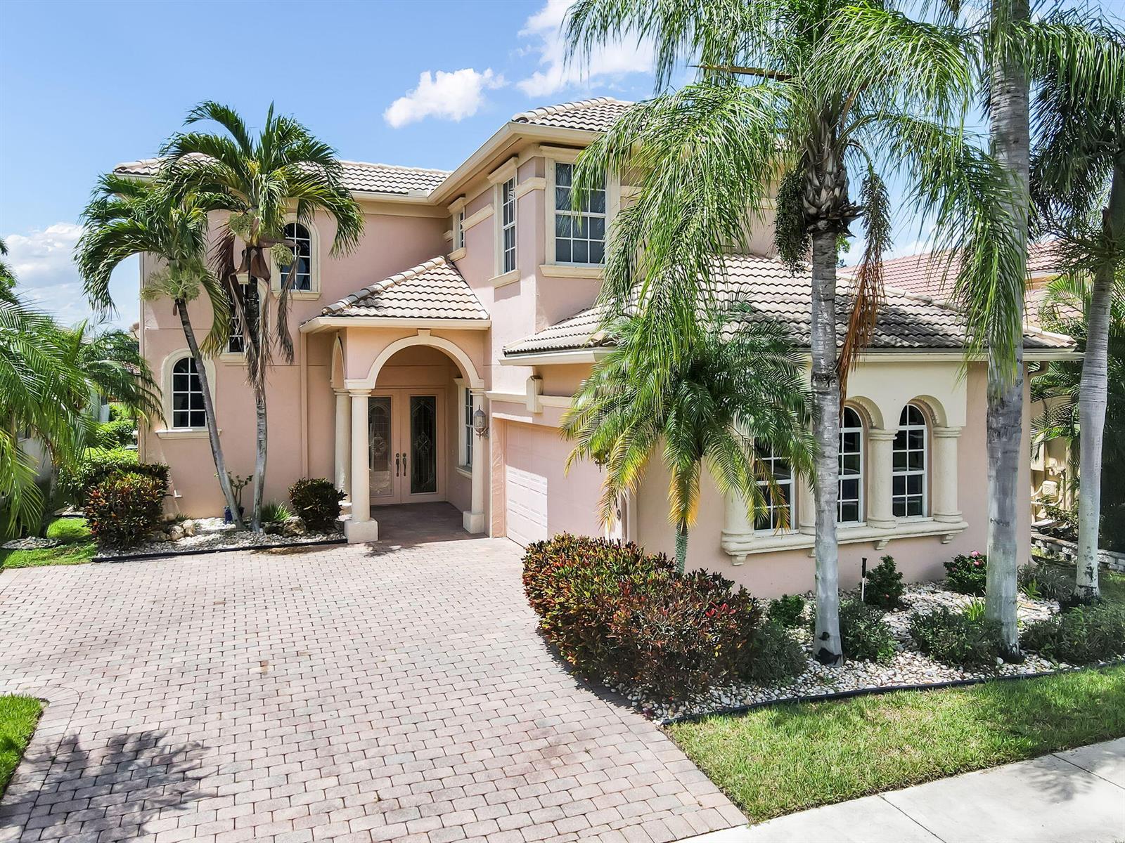 A two-story pink stucco house features a tiled roof, arched entryway, and a paved driveway — 7049 Veneto Drive, Boynton Beach FL 33437, BOYNTON BEACH, FL