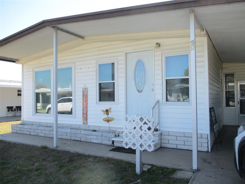 The exterior of a white mobile home features a front porch, siding, and a door — 34542 SWEETPEA LANE, ZEPHYRHILLS, FL