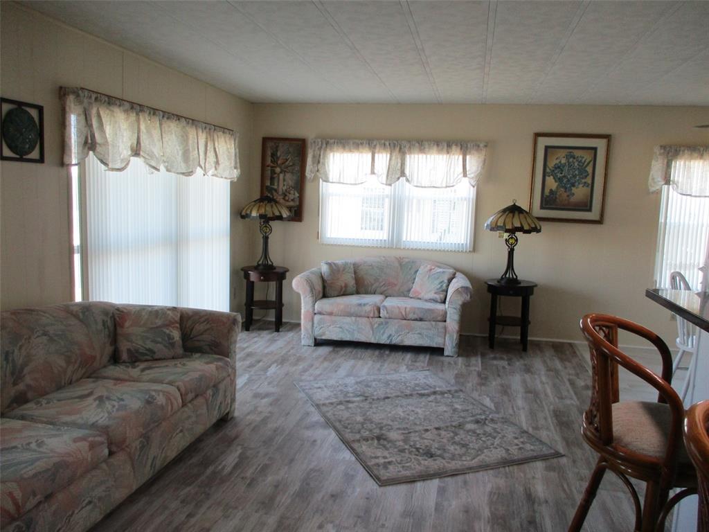 A living room with floral sofas, wood-look flooring, and two stained-glass lamps on end tables — 34542 SWEETPEA LANE, ZEPHYRHILLS, FL