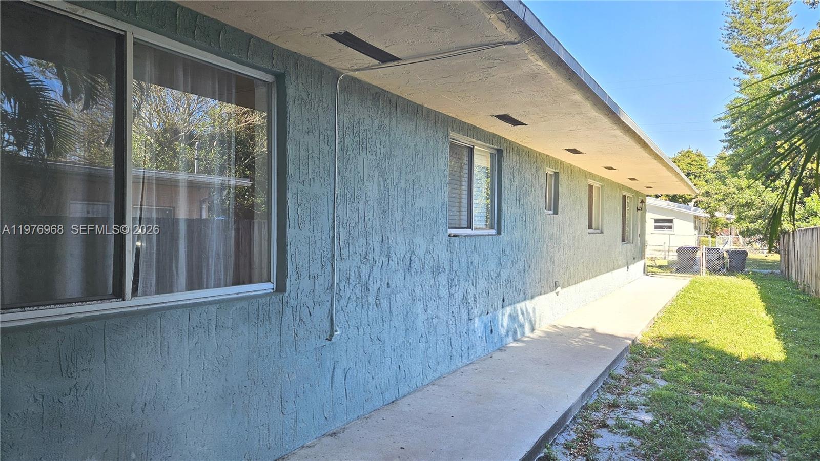 The exterior of a blue stucco house features a concrete walkway and several windows — 2411 Thomas St, Hollywood FL 33020, HOLLYWOOD, FL