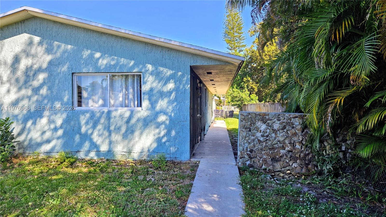 A blue stucco house exterior features a concrete walkway leading to a recessed entrance — 2411 Thomas St, Hollywood FL 33020, HOLLYWOOD, FL