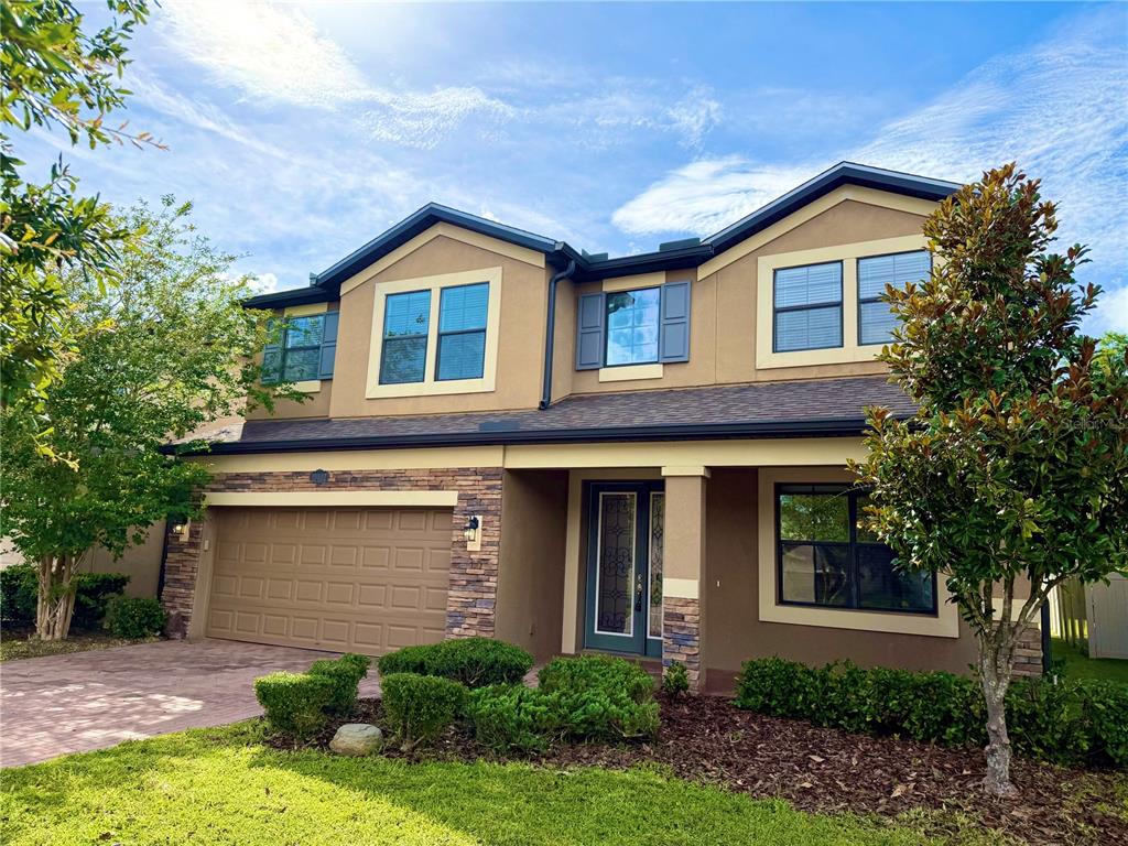 A two-story house with a tan stucco exterior, stone accents, and a two-car garage — 19522 WHISPERING BROOK DRIVE, TAMPA, FL
