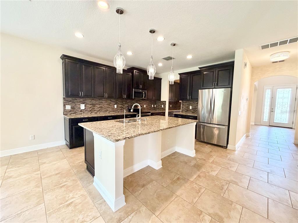 A kitchen features dark wood cabinets, granite countertops, a central island, and tile flooring — 19522 WHISPERING BROOK DRIVE, TAMPA, FL