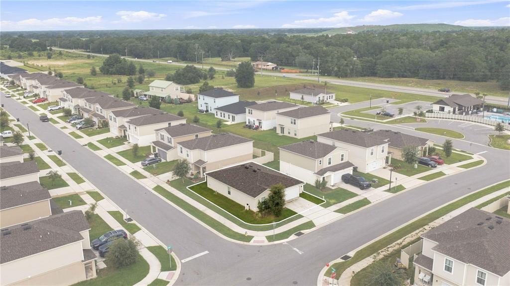 An aerial view shows a suburban neighborhood with a single-story house highlighted on a corner lot — 1876 IOWA DRIVE, SUMTERVILLE, FL