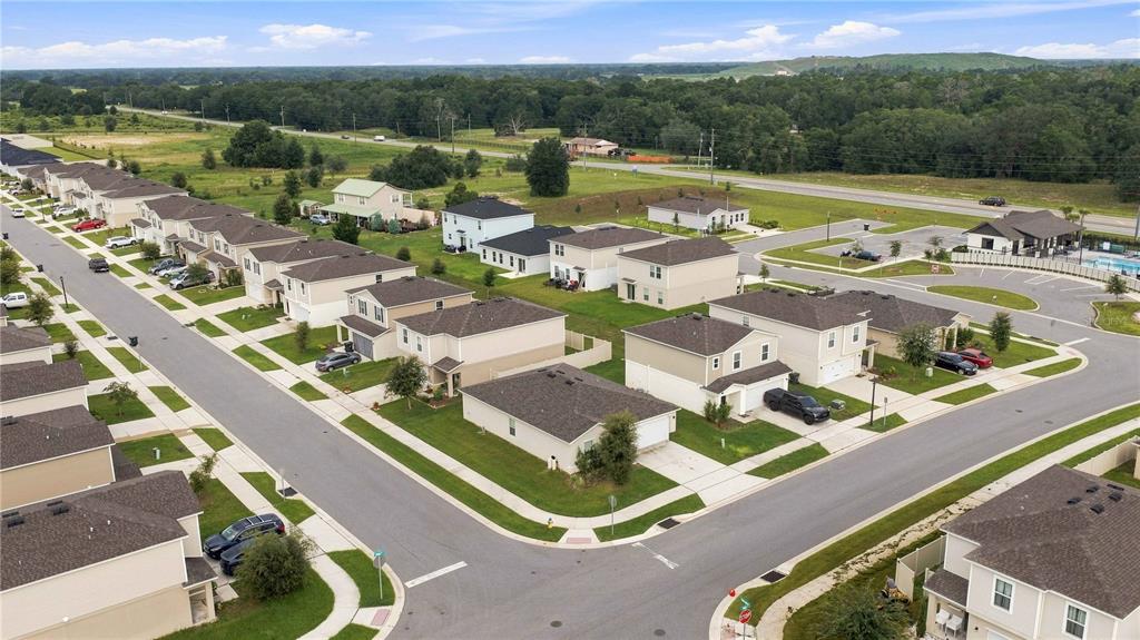 An aerial view shows a suburban neighborhood with multiple two-story houses and paved streets — 1876 IOWA DRIVE, SUMTERVILLE, FL