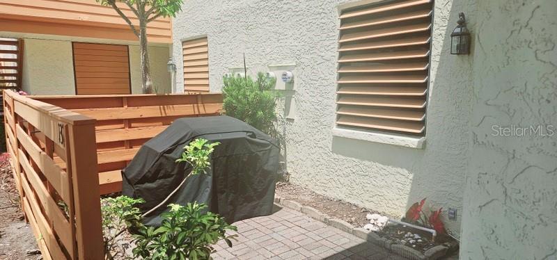 A patio area features a covered grill, a wooden privacy fence, and a window with shutters — 132 WILD PALM DRIVE UNIT 132, BRADENTON, FL