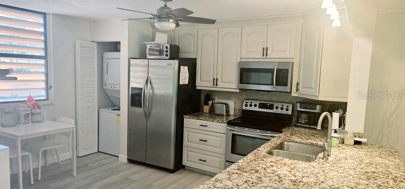 A kitchen features white cabinets, granite countertops, stainless steel appliances, and a ceiling fan — 132 WILD PALM DRIVE UNIT 132, BRADENTON, FL