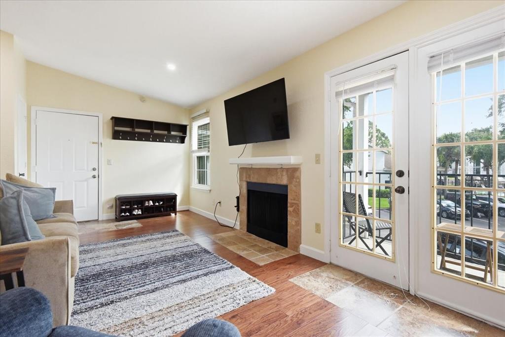 A living room features a fireplace, a wall-mounted television, wood flooring, and glass-paned doors — 2550 N ALAFAYA TRAIL UNIT 11206, ORLANDO, FL