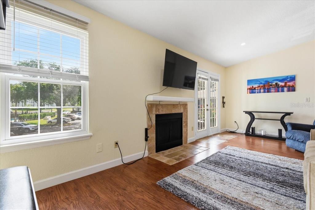 A living room features hardwood floors, a fireplace with a television above, and a window — 2550 N ALAFAYA TRAIL UNIT 11206, ORLANDO, FL