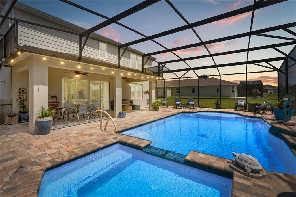 A screened-in patio features a swimming pool, a spa, and a covered dining area — 10260 SPRING LAKE DRIVE, CLERMONT, FL