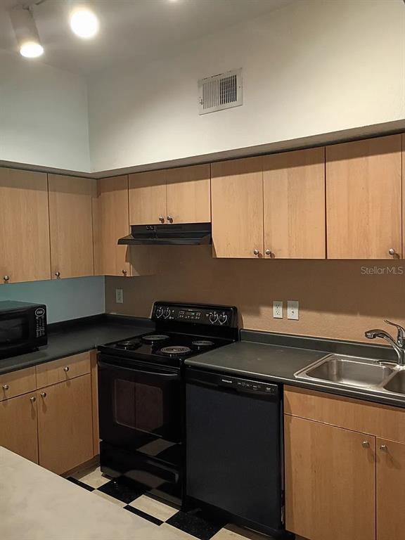A kitchen features light wood cabinets, black appliances, and a black countertop with a sink — 520 ARMENIA AVENUE S UNIT 1234, TAMPA, FL