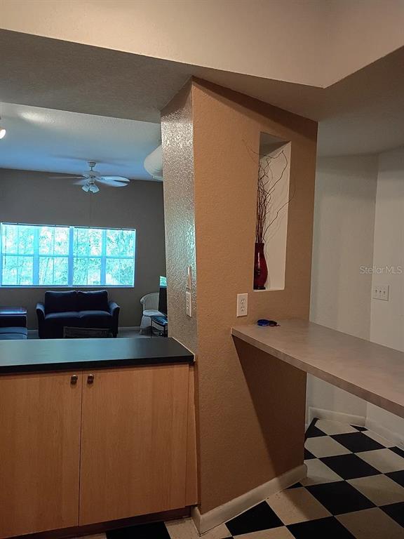 A kitchen counter and breakfast bar overlook a living room with a ceiling fan — 520 ARMENIA AVENUE S UNIT 1234, TAMPA, FL