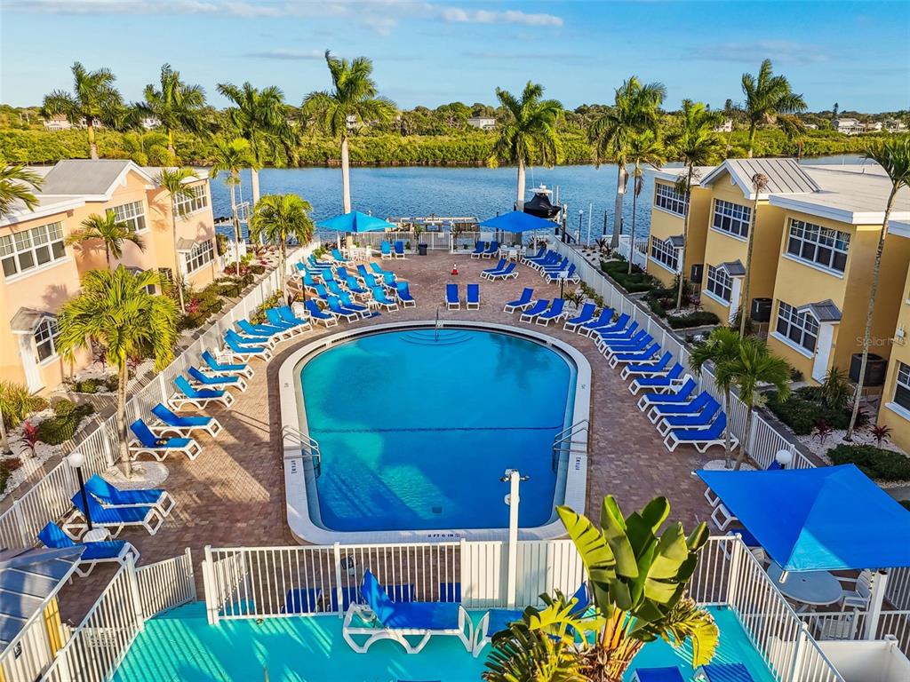 An elevated view of a swimming pool surrounded by lounge chairs and multi-story yellow buildings — 19417 GULF BOULEVARD UNIT F107, INDIAN ROCKS BEACH, FL